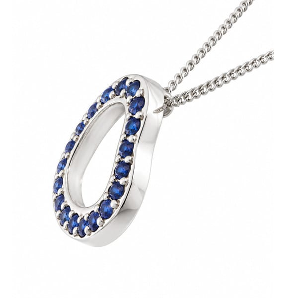 A heart shaped pendant with grain set round blue sapphires. designed to sit at an angle designer modern pendant gold platinum chain