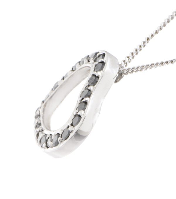 A heart shaped pendant with grain set round black diamonds. designed to sit at an angle designer modern pendant gold platinum