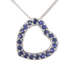 A heart shaped pendant with grain set round blue sapphires. designed to sit at an angle designer modern pendant gold platinum chainplatinum chain