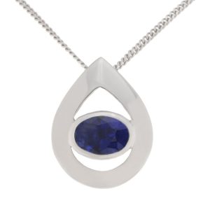 A modernist pear shape tear drop pendant with an oval blue sapphire centre stone in rubover setting. designer modern gold platinum chain