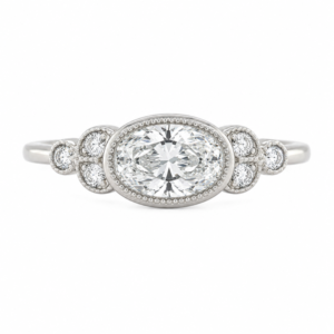 Classic art deco style ring oval shape cut diamond centre stone millgrain round diamonds shoulders vintage engagement platinum gold