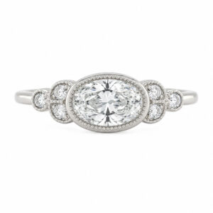Classic art deco style ring oval shape cut diamond centre stone millgrain round diamonds shoulders vintage engagement platinum gold