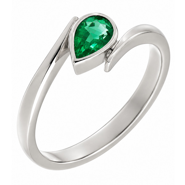 A modern crossover style ring with a solitaire pear shape green emerald in a rubover setting modernist contemporary design designer platinum gold
